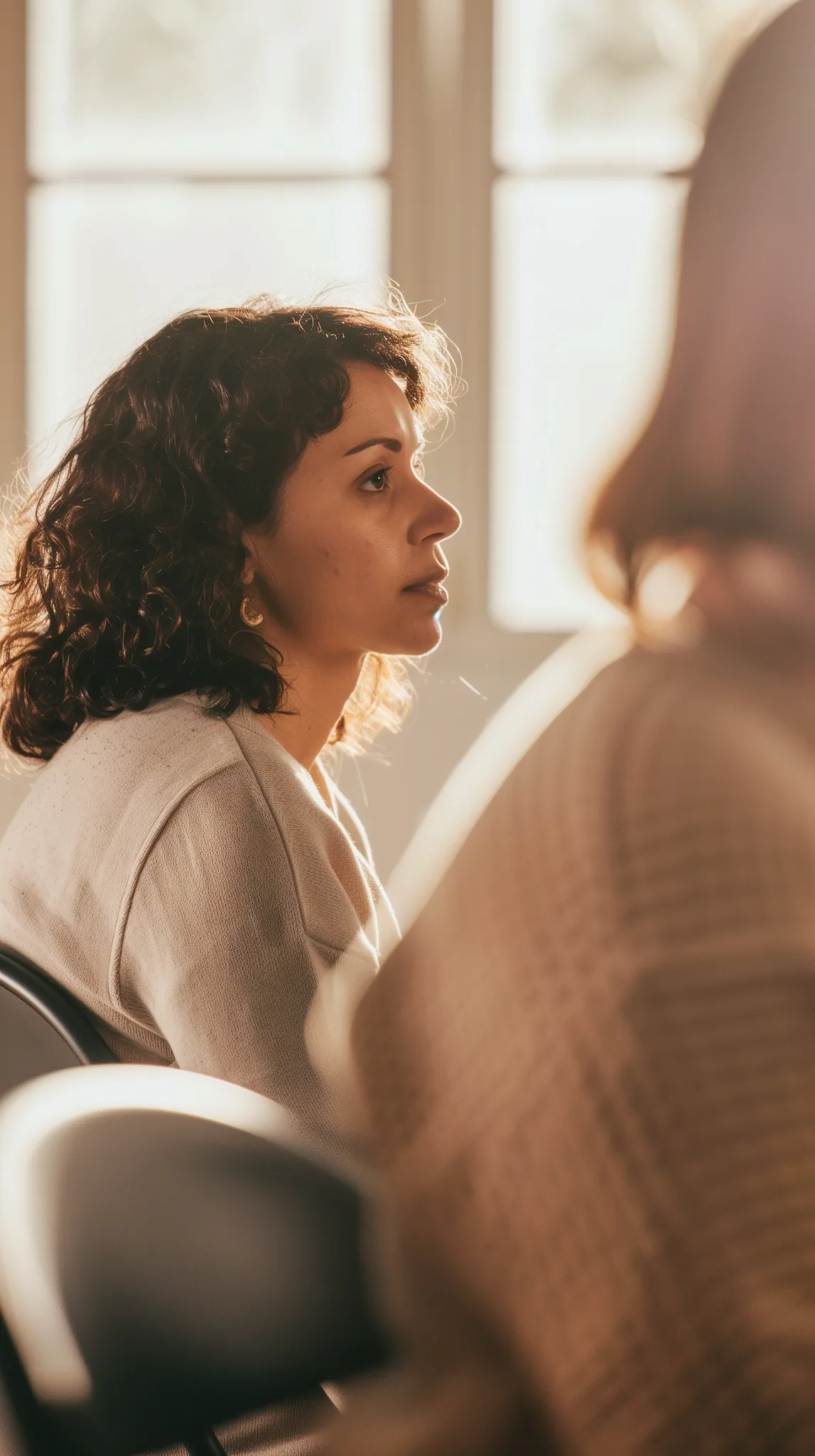 Participant listening during a mental health first aid training session in Kelowna, seated in a small group with soft natural light.